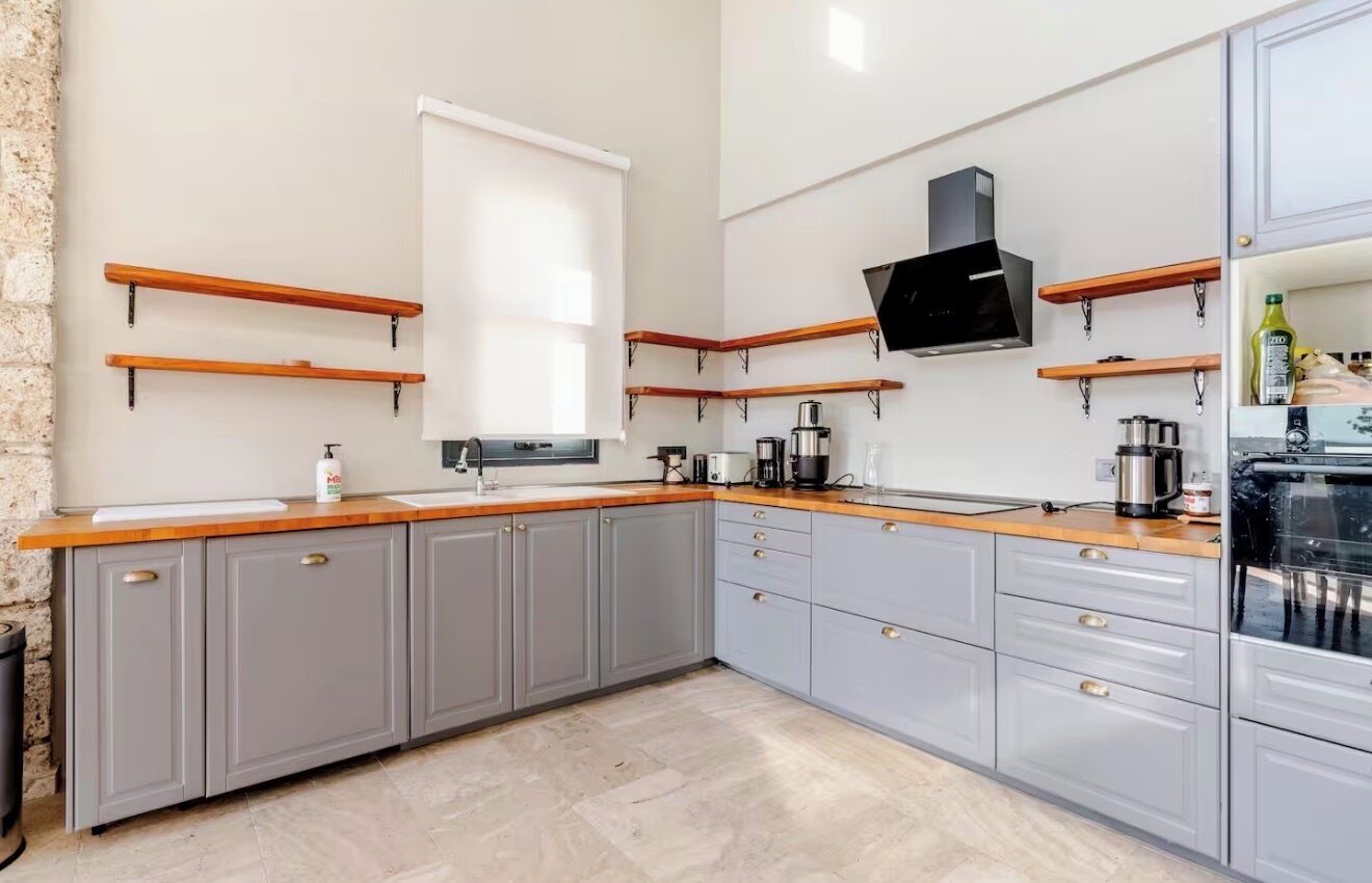 Una cocina con gabinetes grises, encimeras de madera y estanterías integradas.