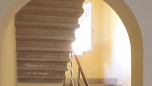 Eine Treppe mit einem Holnändergeländer und einem Mülleimer am Fuß.