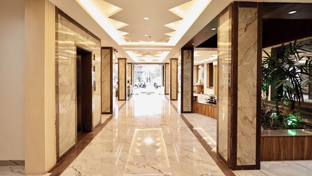 A hotel lobby with a marble floor, a reception desk, and a plant display. - Hotel Maniratna Premium (Sanwer)