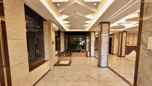 A hotel lobby with marble flooring, a central staircase, and a reception desk. - Hotel Maniratna Premium (Sanwer)