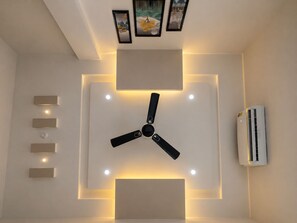 Ventilatore a soffitto, illuminazione incassata e condizionatore d'aria a parete in una stanza.