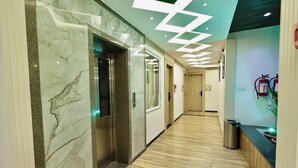 A hallway with marble walls, wooden flooring, and a modern ceiling design. - Hotel Maniratna Premium (Sanwer)