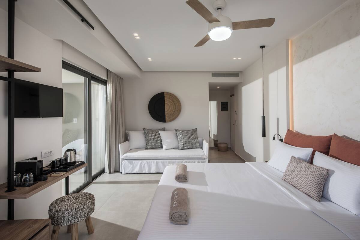 Ein modernes Hotelzimmer mit einem Bett, einem Schreibtisch, einem Stuhl und einem Deckenventilator.