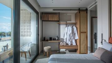 Een moderne hotelkamer met een groot raam, een bed, een bureau met een computer, een stoel en een kledingkast.