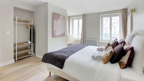 Un dormitorio con cama, armario, ventana y radiador.