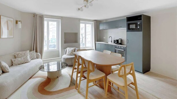 Una sala moderna con sofá, mesa de centro y comedor. Incluye una cocina con microondas, horno y armarios.