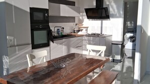 Une cuisine moderne avec des meubles blancs, une table à manger en bois et un four encastré.