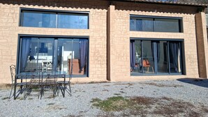 Un bâtiment à deux étages doté de grandes fenêtres et d’un patio avec une table et des chaises.