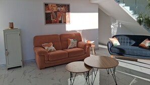 Un salon moderne avec un canapé, deux tables d’appoint et un escalier.