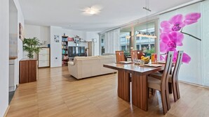 Ein modernes Wohnzimmer mit einem Holzesstisch, einer Couch und einem Fernseher.