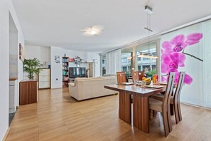 Ein modernes Wohnzimmer mit einem Holzesstisch, einer Couch und einem Fernseher.