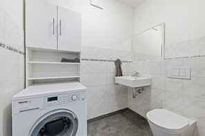 Een kleine badkamer met een wasmachine, wastafel en toilet.