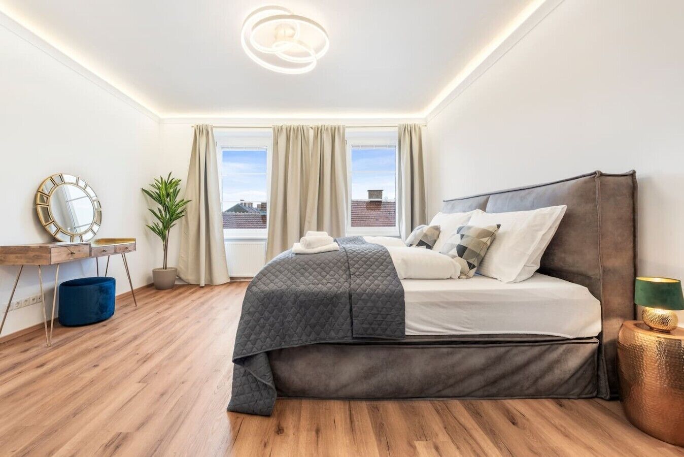A modern bedroom with a bed, bedside table, lamp, and a view of the city.