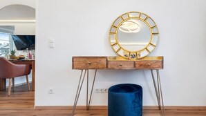 Ein hölzerner Waschtisch mit einem goldfarbenen Spiegel, einer blauen Vase und Holzboden.