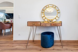 Ein hölzerner Waschtisch mit einem goldfarbenen Spiegel, einer blauen Vase und Holzboden.