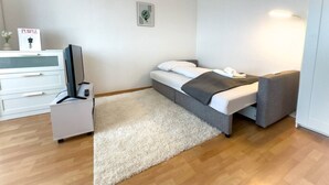 Ein modernes Schlafzimmer mit einem Bett, einem Nachttisch, einem Fernseher und einer weißen Kommode.