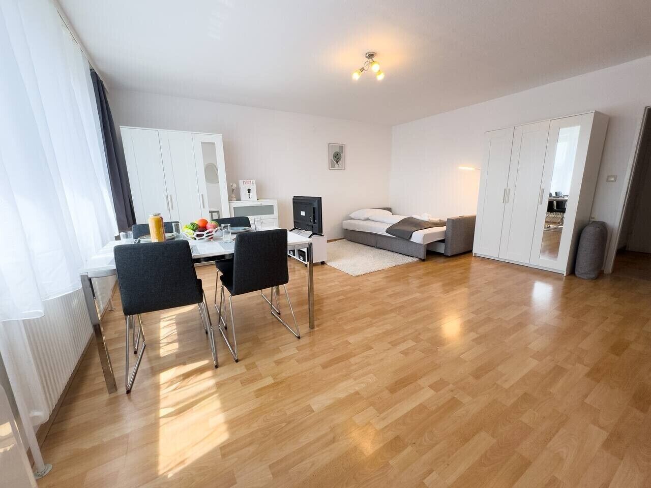 A modern living room with a dining area, a sofa, and a TV.