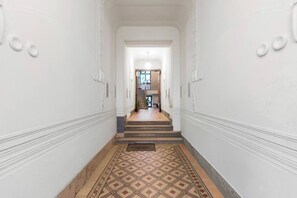 A hallway with a patterned floor, a staircase, and a door leading to another room. - 2Bedroom Vintage Apartment+Garden, near Schönbrunn (Vienna)