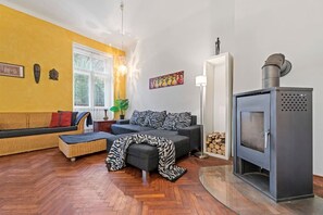 Un salon avec un canapé, un fauteuil, une cheminée et une fenêtre.