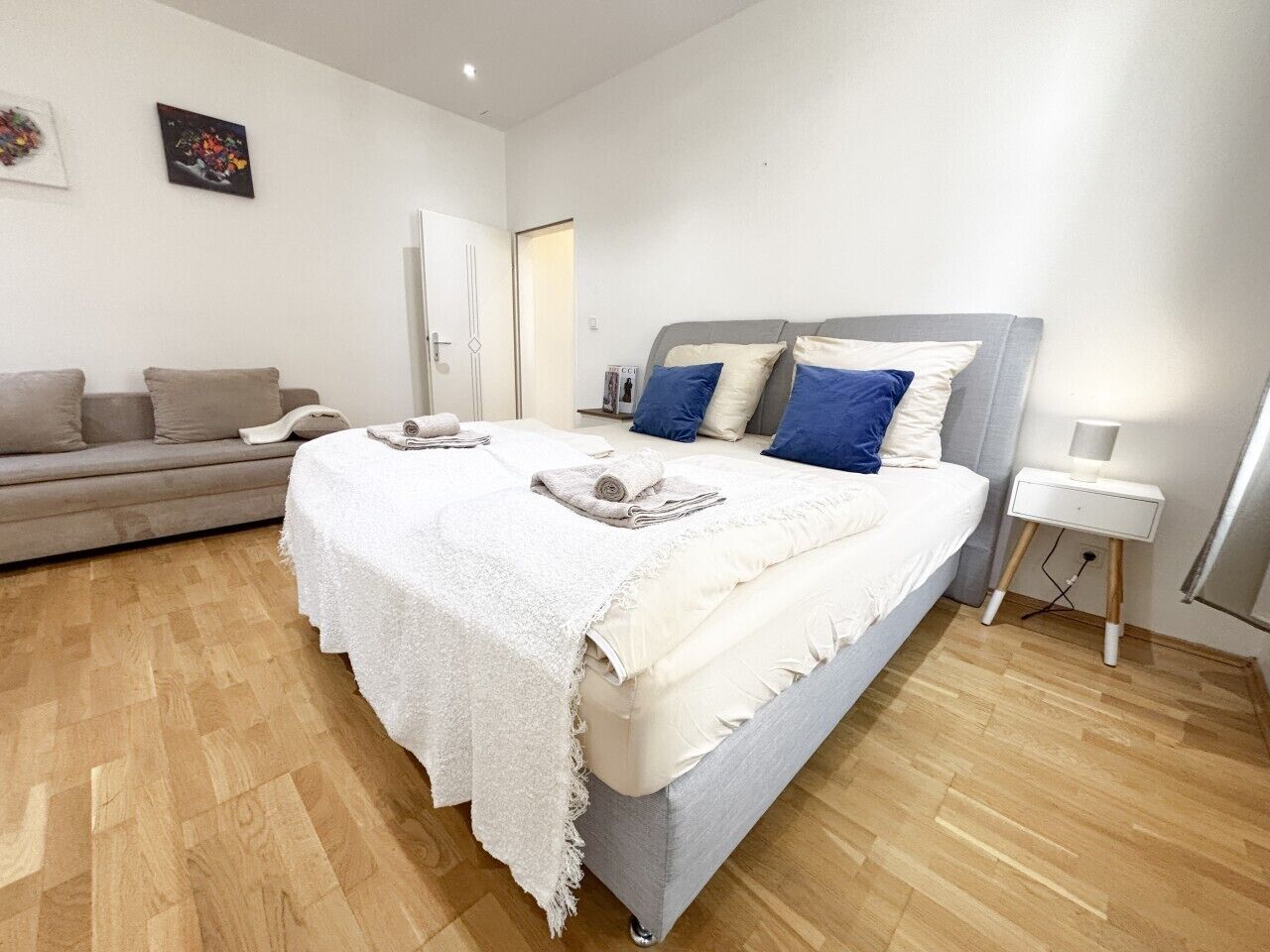 Une chambre à coucher avec un lit, une table de chevet, une lampe, un canapé et une porte.