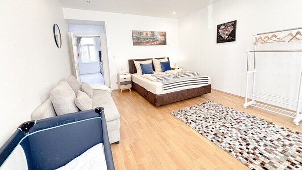 Een moderne slaapkamer met een bed, een bank, een nachtkastje, een hanglamp en een wanddecoratie.