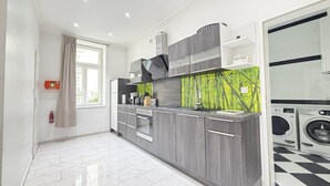 Een moderne keuken met grijze kastjes, een ingebouwde oven en een groene spatwand.