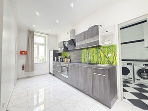Eine moderne Küche mit grauen Schränken, einem eingebauten Ofen und einer grünen Spritzschutzwand.