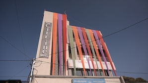 Ein Hotel mit einem vertikalen Schild, auf dem "The Citine Hotel" steht, und einer Fassade, die mit farbenfrohen Vorhängen verziert ist.