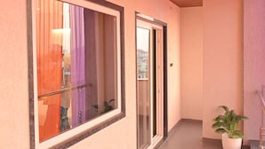 Ein Flur mit großem Fenster, einer Tür und einer Topfpflanze.