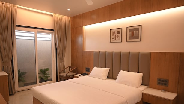 Ein modernes Hotelzimmer mit einem großen Bett, Holzvertäfelung, einem Schreibtisch und einer Schiebetür zum Außenbereich.