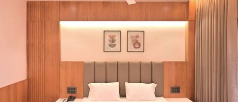 Une chambre d’hôtel moderne avec un grand lit, deux tables de chevet, un ventilateur de plafond et un lambris en bois.