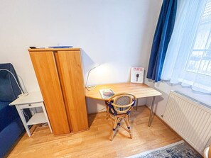 A small room with a wooden desk, a chair, a wardrobe, a radiator, and a window with curtains. - Studio mit Balkon, im Zentrum, Klimaanlage (Vienna)