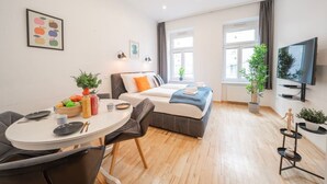 Ett modernt hotellrum med en säng, en matplats, en TV och ett fönster med gardiner.