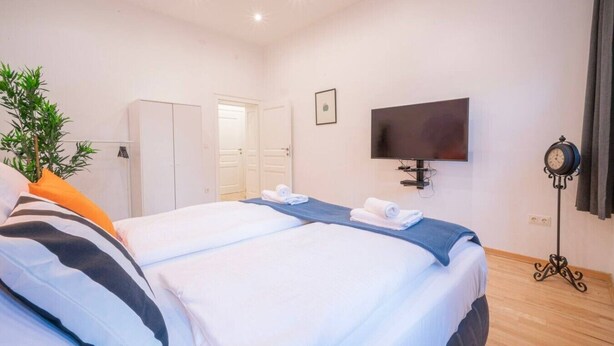 Ett hotellrum med två sängar, en tv, en väckarklocka och en växt.