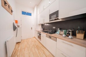 Eine moderne Küche mit weißen Schränken, einer Mikrowelle, einem Toaster und einer Kaffeemaschine.