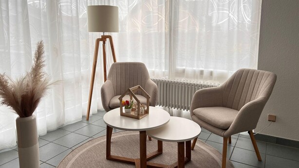 A living room with two armchairs, a round coffee table, a floor lamp, and a radiator. - Vacation apartment Allensbach (Allensbach)
