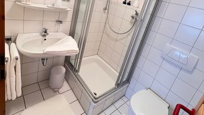 A bathroom with a glass-enclosed shower, a sink, a toilet, and a mirror. - Vacation apartment Allensbach (Allensbach)