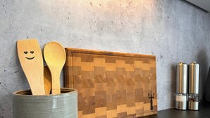 A kitchen with a wooden block wall, a ceramic container with wooden spoons, and stainless steel containers on the counter. - Vacation apartment Allensbach (Allensbach)