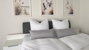 A bedroom with a bed, pillows, and three framed artworks on the wall. - Vacation apartment Allensbach (Allensbach)