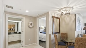 A dining area with wicker chairs, a glass table, a chandelier, and a mirror on the wall. - Inviting 2 Bedroom Condo in Westwinds at Sandestin Golf and Beach Resort (Miramar Beach)