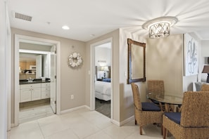 A dining area with wicker chairs, a glass table, a chandelier, and a mirror on the wall. - Inviting 2 Bedroom Condo in Westwinds at Sandestin Golf and Beach Resort (Miramar Beach)