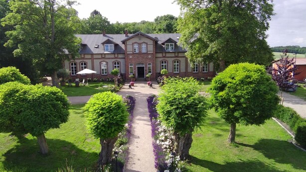 Ein großes, zweistöckiges Gebäude mit einer symmetrischen Fassade, einem zentralen Eingang und einem gepflegten Garten mit einem Weg zum Eingang.