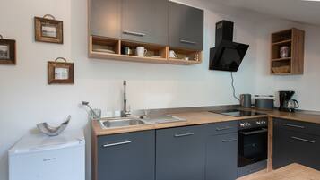 A modern kitchen with grey cabinets, a built-in oven, and a coffee machine.