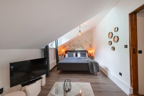 Ein modernes Schlafzimmer mit Flachbildfernseher, einem Bett mit dunklem Kopfteil und einer Wand mit runden Spiegeln.