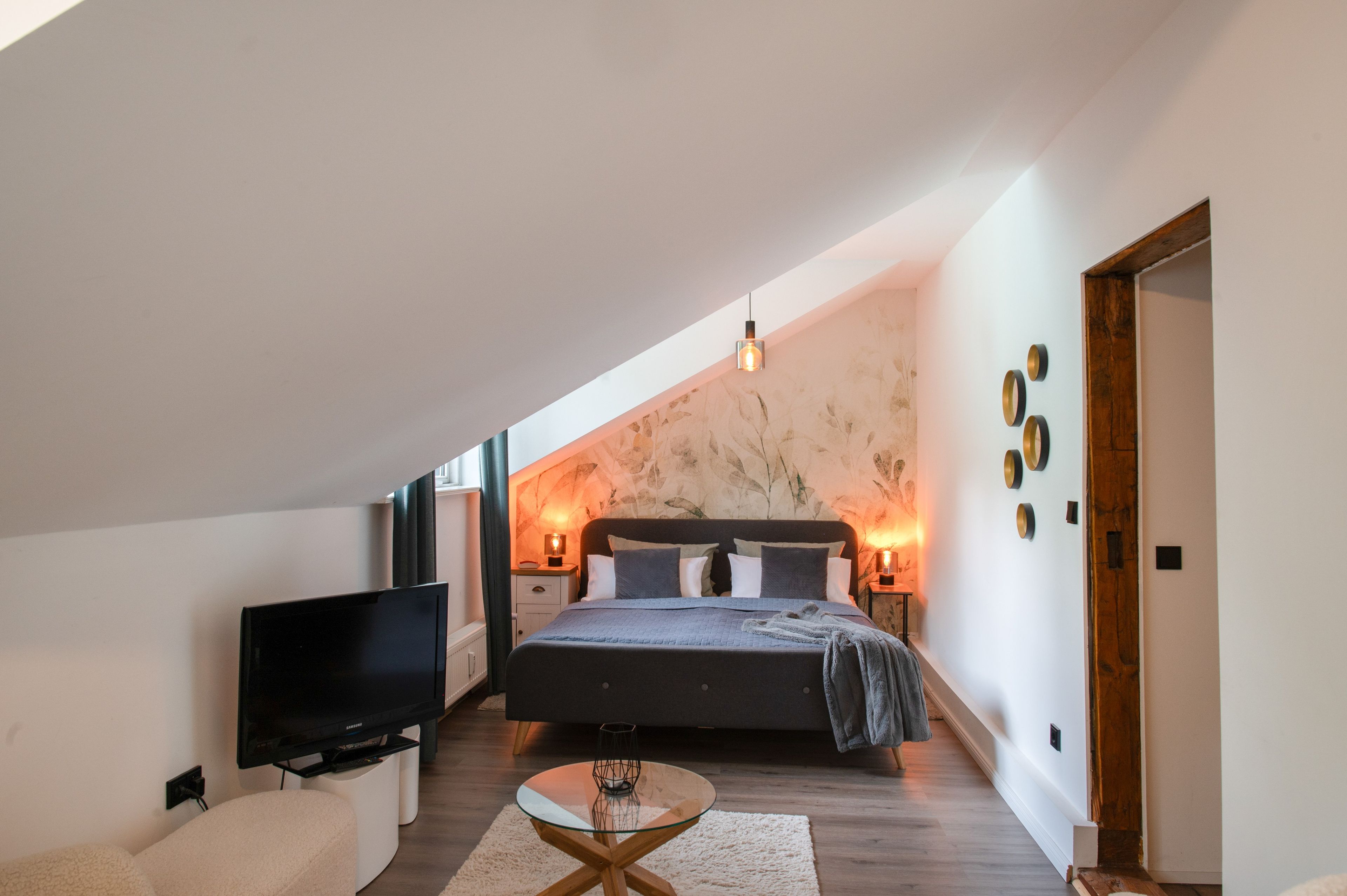 Een moderne slaapkamer met een groot bed, een flatscreen televisie en een glazen salontafel.