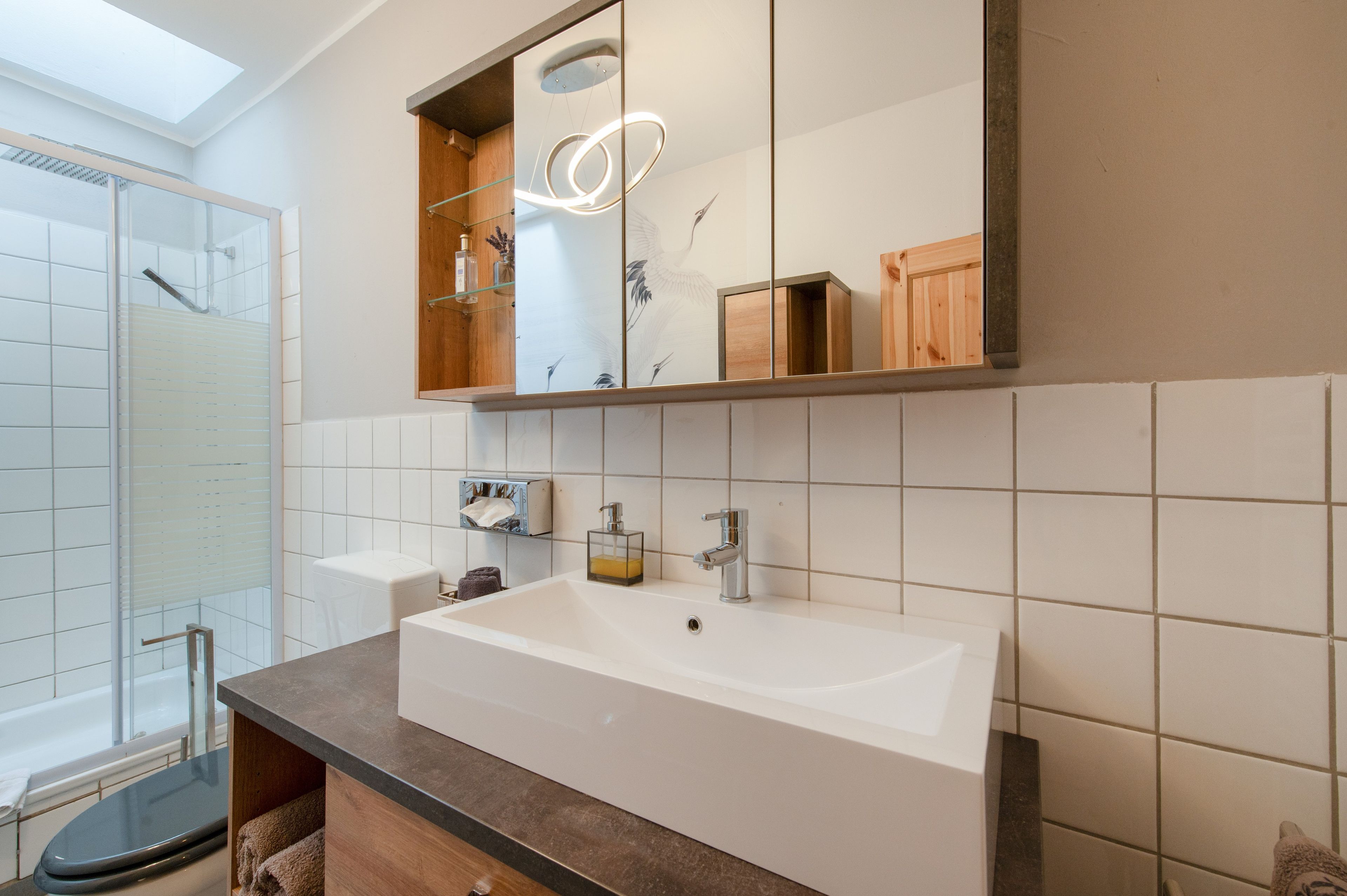 A bathroom with a large mirror, a white sink, and a glass shower enclosure.