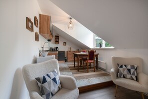 Une chambre à coucher confortable, aménagée dans un espace mansardé, avec un coin repas et une cuisine.