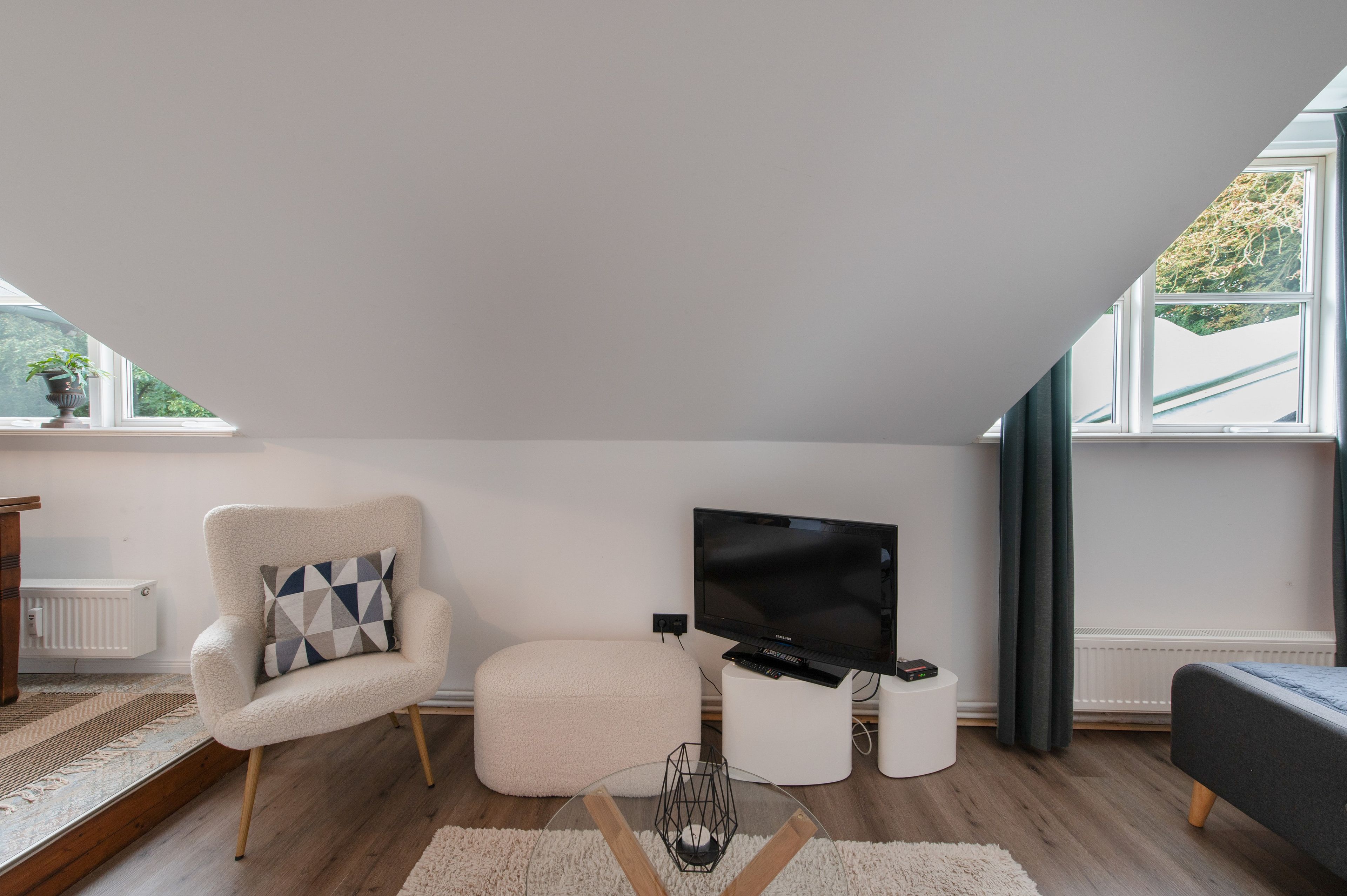 A modern living room with a sofa, a chair, a flat-screen TV, and a small table.