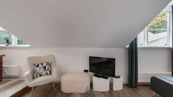 A modern living room with a sofa, a chair, a flat-screen TV, and a small table.