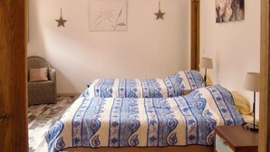 Een slaapkamer met een bed, een stoel, een dressoir en wanddecoraties.
